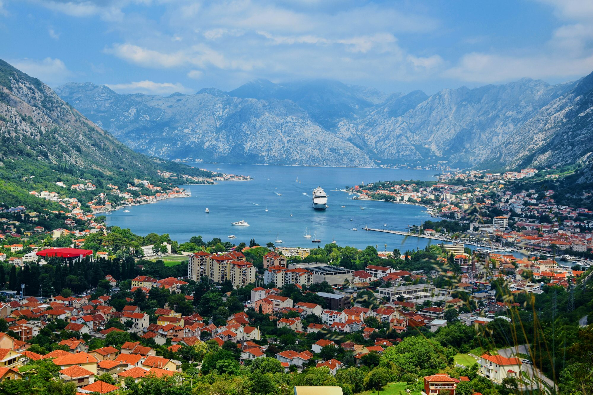 Panoramic view of the Bay of Kotor with mountains, red-roofed town and calm blue water